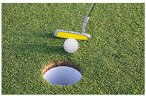 Putter and golf ball near hole